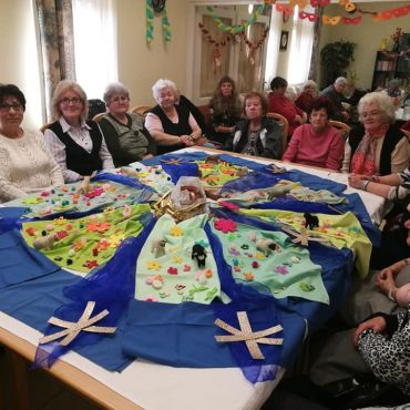 Klubtagjaink interaktív mesés foglalkozáson. A foglalkozás végén a csoport tagok mosolyogva ülnek az asztal körül.