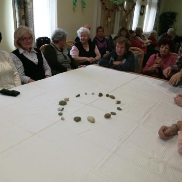 A mese fonala lassan bontakozik ki, Az asztal körül ülő klubtagok, a mese része ként a kiválasztott köveket középre helyezték.